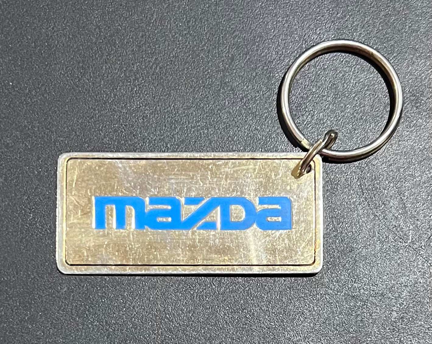 Mazda Logo Gold Plated Metal Keychain with Engravable Backside N.O.S. Relic has been store safely away for decades and shows some wear but vintage from the 1980s